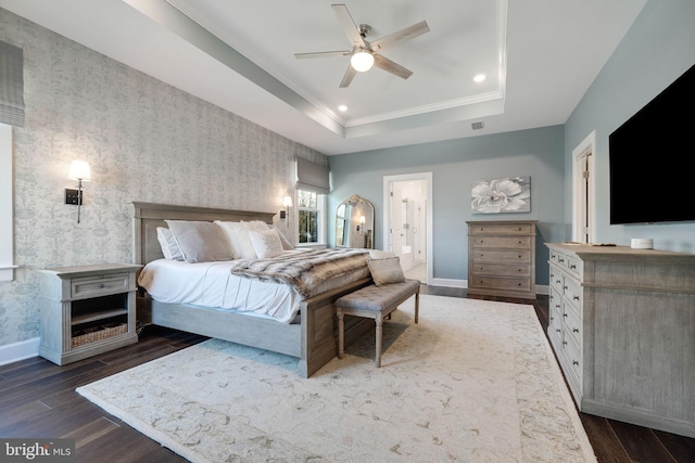 bedroom featuring crown molding, ensuite bath, a tray ceiling, and dark hardwood / wood-style floors