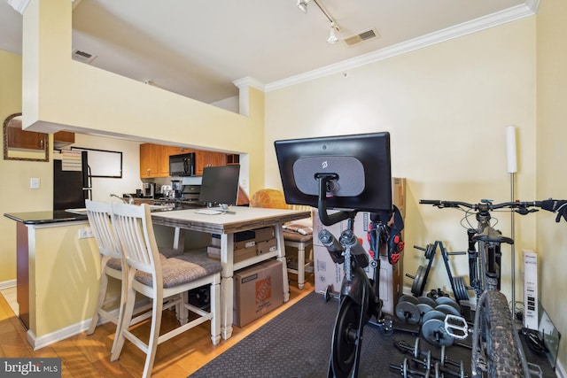 workout area featuring light wood-style floors, visible vents, and crown molding