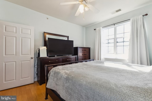 bedroom featuring a ceiling fan, visible vents, and light wood finished floors