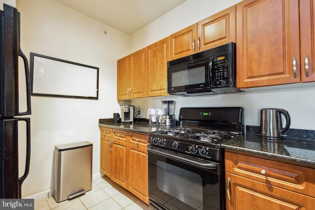 kitchen featuring black appliances, light tile patterned floors, dark stone counters, and brown cabinetry