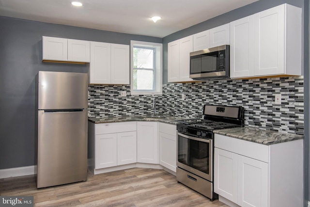 kitchen featuring sink, tasteful backsplash, appliances with stainless steel finishes, dark stone counters, and white cabinets