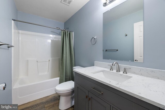 full bathroom with visible vents, toilet, shower / tub combo with curtain, wood finished floors, and vanity