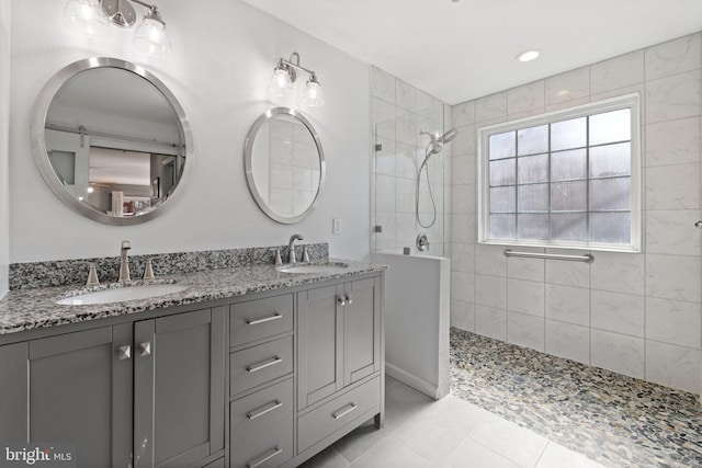 bathroom featuring tile patterned flooring, double vanity, a walk in shower, and a sink