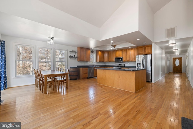 kitchen featuring light wood-style floors, stainless steel appliances, dark countertops, and visible vents