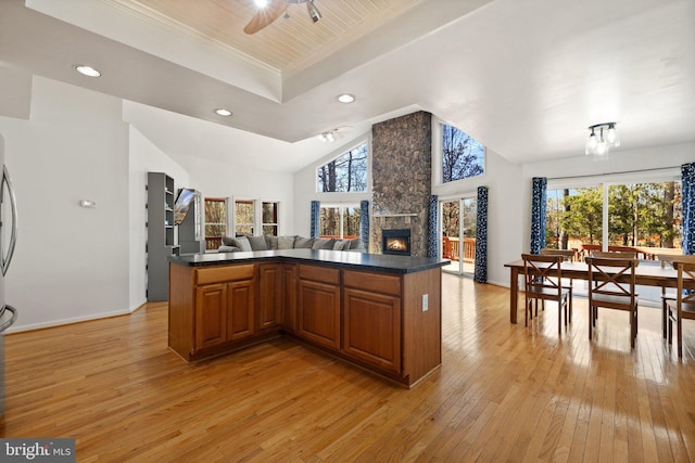 kitchen featuring brown cabinets, light wood-style flooring, plenty of natural light, dark countertops, and open floor plan