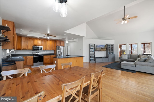 kitchen with dark countertops, a center island, stainless steel appliances, and a sink