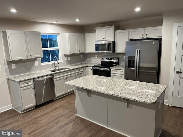 kitchen featuring sink, white cabinets, a center island, stainless steel appliances, and light stone countertops