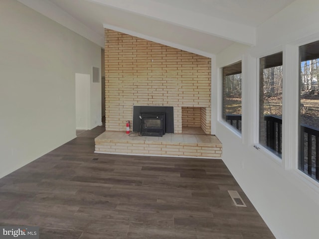 unfurnished living room featuring vaulted ceiling with beams, dark wood-type flooring, and a wood stove