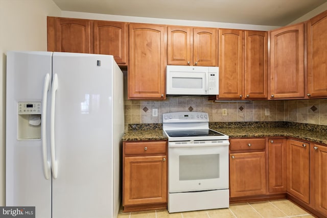 kitchen with tasteful backsplash, white appliances, and dark stone counters