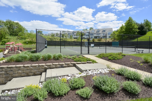 view of tennis court featuring a playground