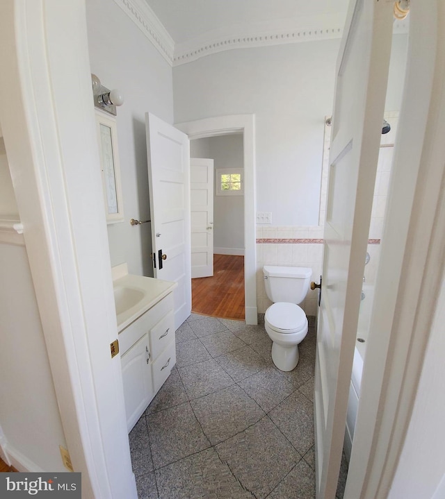 bathroom with vanity, ornamental molding, tile walls, and toilet