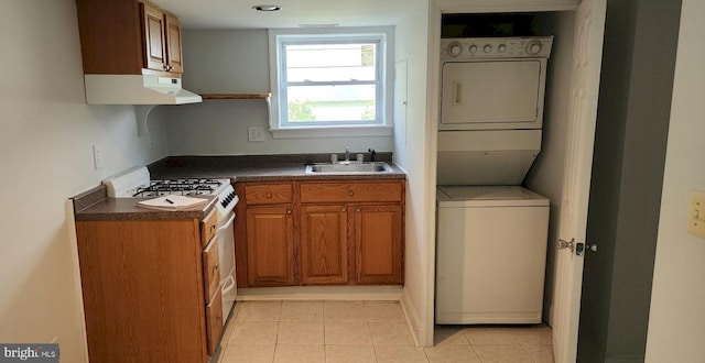 kitchen featuring white range with gas cooktop, sink, light tile patterned floors, and stacked washing maching and dryer