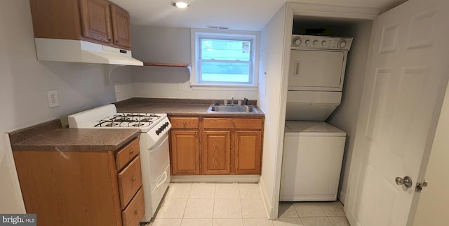 kitchen with stacked washer and dryer, white gas range, sink, and light tile patterned floors