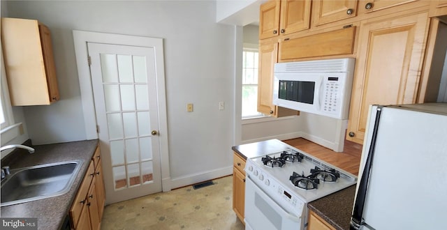 kitchen featuring sink, light brown cabinetry, and white appliances