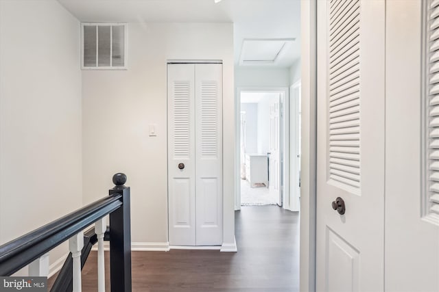 hall with dark wood finished floors, visible vents, attic access, an upstairs landing, and baseboards