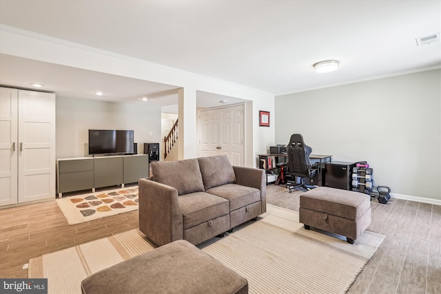 living area featuring stairs, light wood-type flooring, visible vents, and crown molding