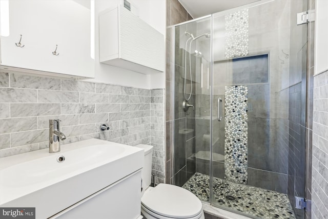 bathroom with a shower stall, tile walls, toilet, and vanity