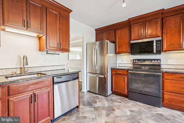 kitchen featuring dark stone counters, stainless steel appliances, and a sink