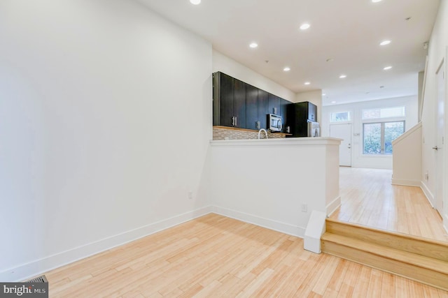 kitchen with hardwood / wood-style floors, decorative backsplash, fridge, and kitchen peninsula