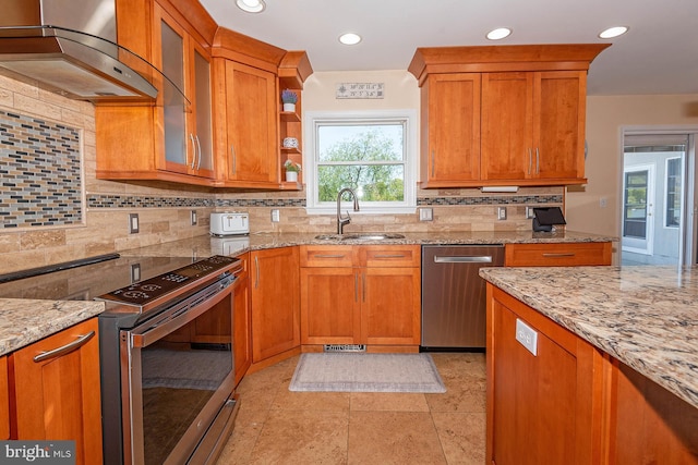 kitchen featuring light stone counters, sink, exhaust hood, and appliances with stainless steel finishes