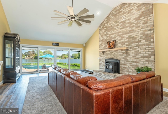 living room with hardwood / wood-style floors, high vaulted ceiling, ceiling fan, and a wood stove