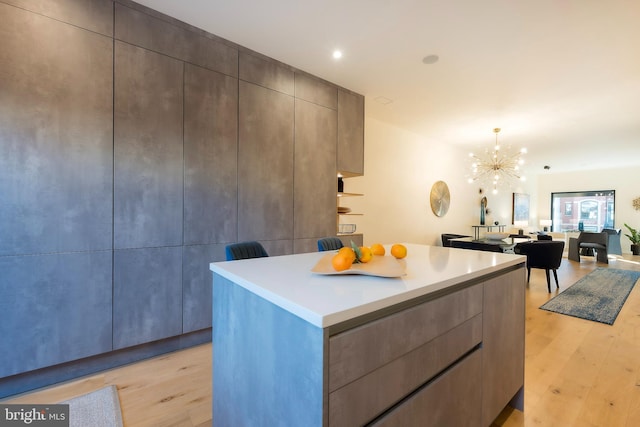 kitchen with hanging light fixtures, a center island, an inviting chandelier, and light hardwood / wood-style floors