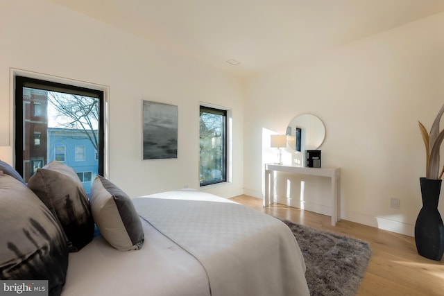 bedroom with multiple windows, access to exterior, and light wood-type flooring