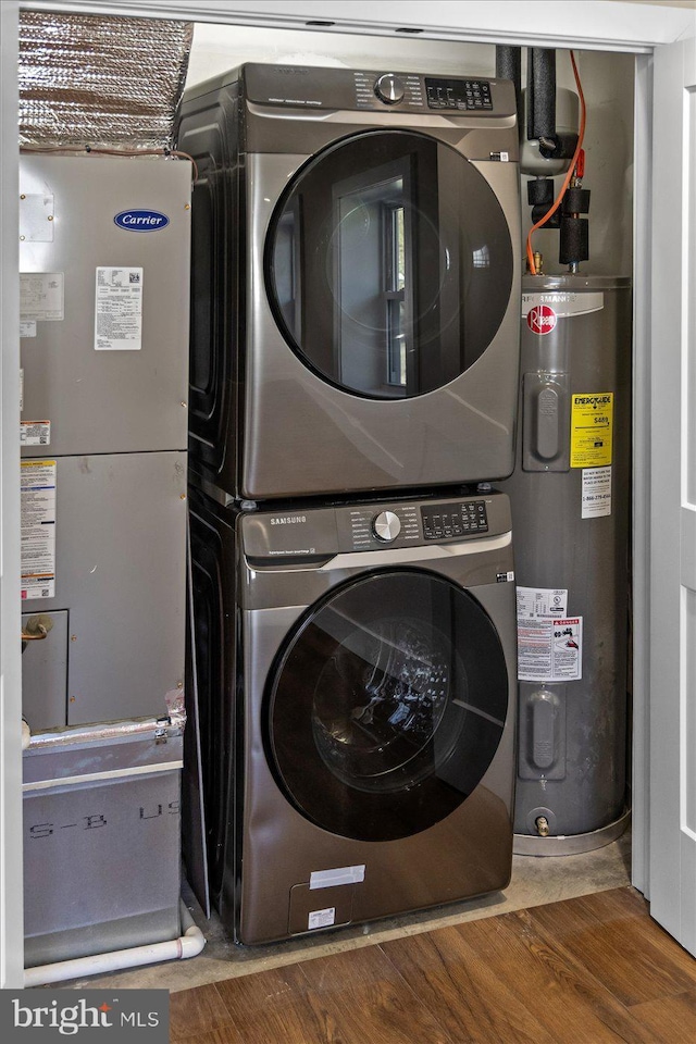 laundry area with dark hardwood / wood-style flooring, stacked washer and dryer, and water heater