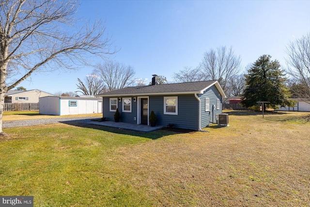 view of front of property featuring central AC unit, a front lawn, and a storage shed