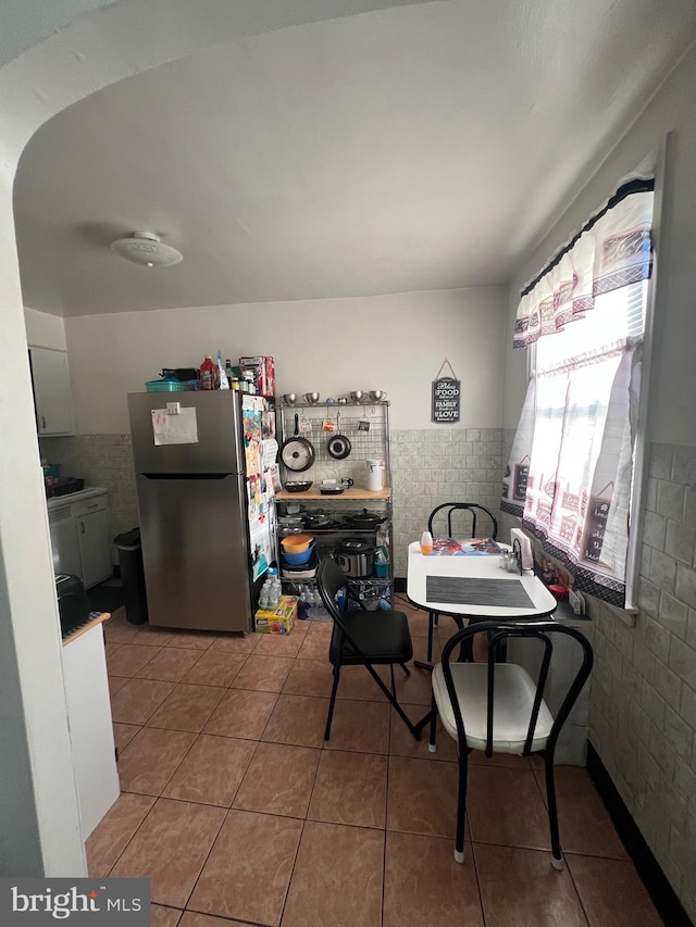 dining space featuring tile patterned floors and tile walls