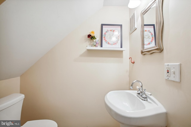 bathroom with sink, vaulted ceiling, and toilet