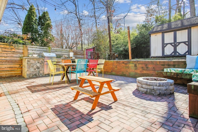 view of patio / terrace featuring an outdoor kitchen, an outdoor fire pit, a grill, and a shed