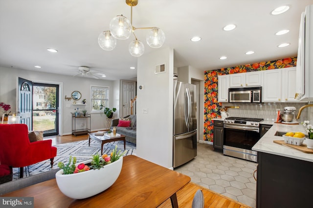 kitchen with tasteful backsplash, sink, white cabinets, hanging light fixtures, and stainless steel appliances