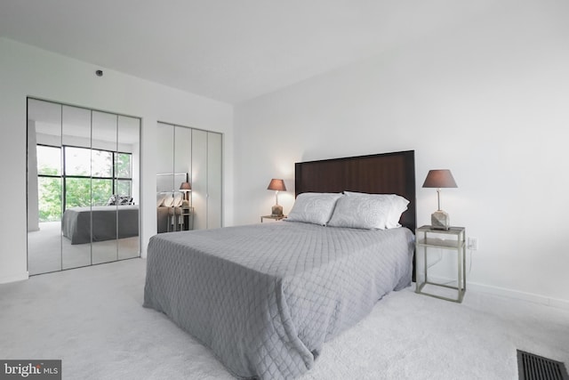 bedroom with light carpet and two closets