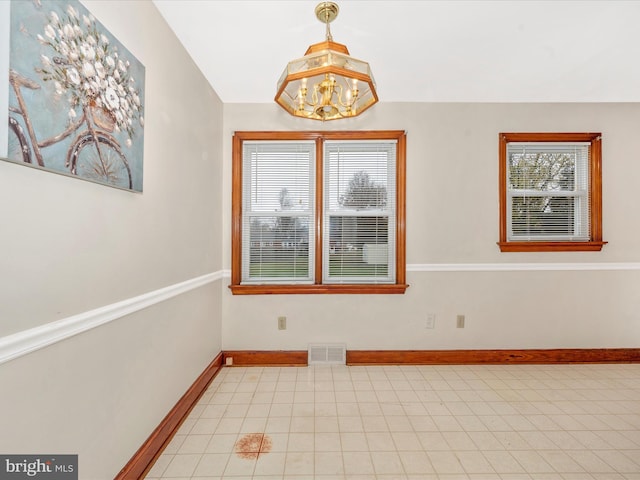 spare room featuring light tile patterned floors, baseboards, visible vents, and a notable chandelier