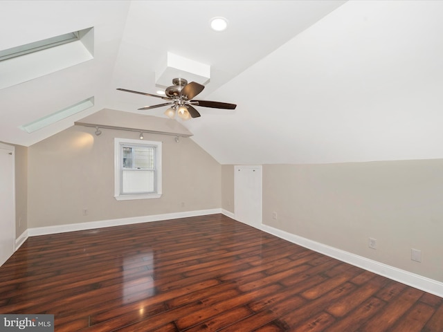 additional living space featuring lofted ceiling with skylight, wood-type flooring, a ceiling fan, and baseboards