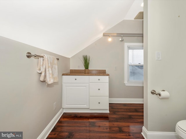 bathroom with toilet, baseboards, vaulted ceiling, and wood finished floors