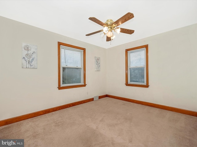 empty room with carpet floors, baseboards, visible vents, and ceiling fan