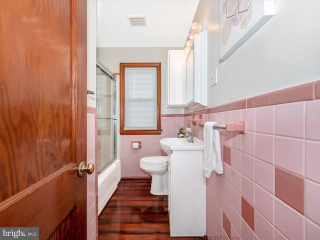 bathroom with visible vents, toilet, wood finished floors, vanity, and tile walls