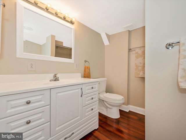 bathroom featuring toilet, baseboards, wood finished floors, and vanity