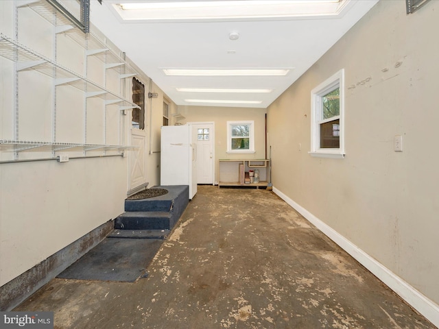 interior space with baseboards and freestanding refrigerator