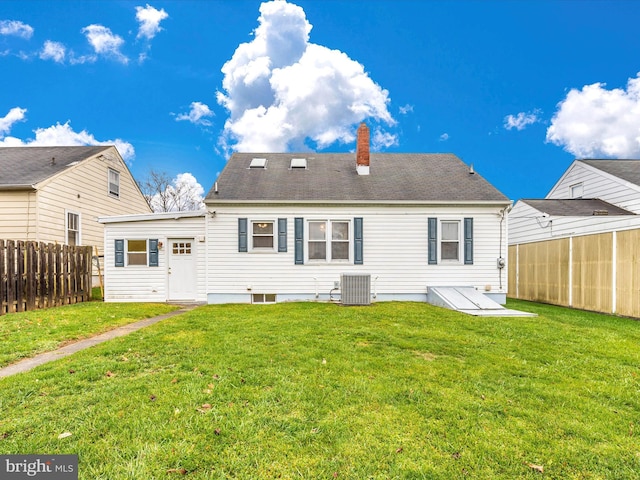 back of house featuring central AC, a yard, a chimney, and fence