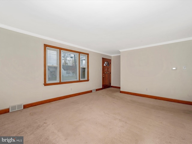 spare room featuring light carpet, ornamental molding, visible vents, and baseboards