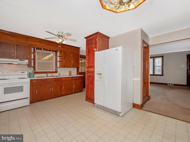 kitchen featuring white appliances, visible vents, light countertops, under cabinet range hood, and a sink