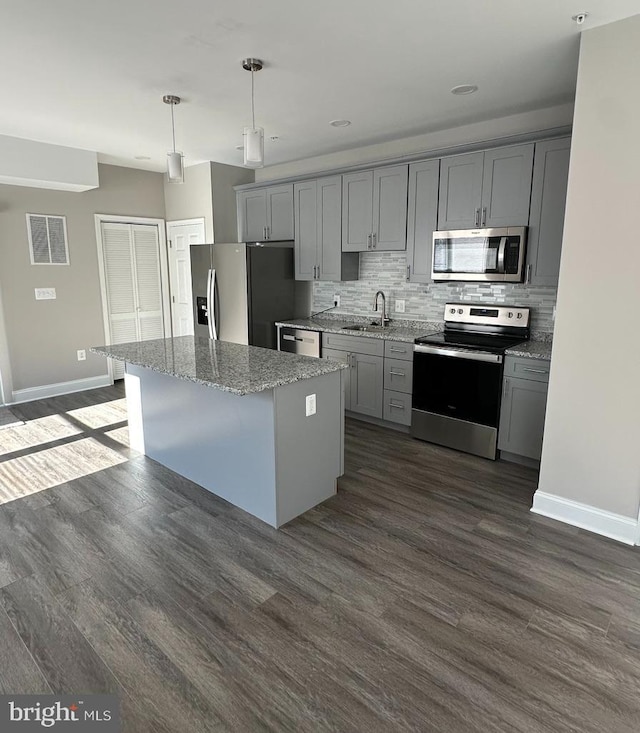 kitchen featuring stainless steel appliances, decorative light fixtures, a kitchen island, and gray cabinetry