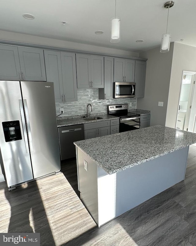 kitchen featuring light stone counters, appliances with stainless steel finishes, dark hardwood / wood-style floors, and gray cabinetry