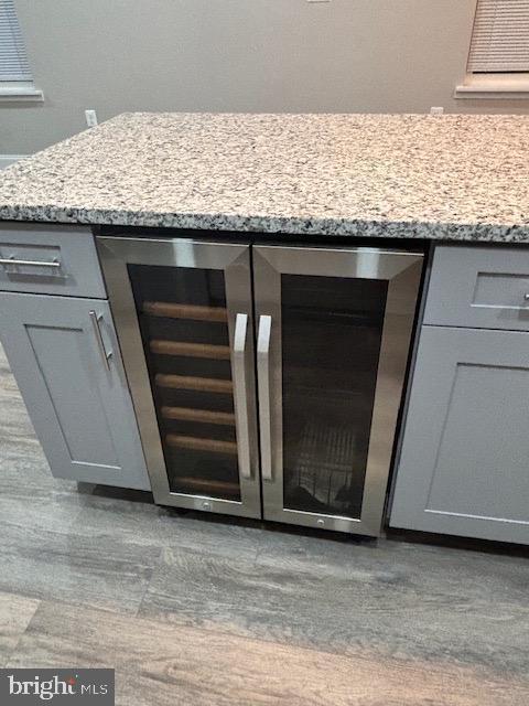 details featuring gray cabinets, light stone countertops, and beverage cooler