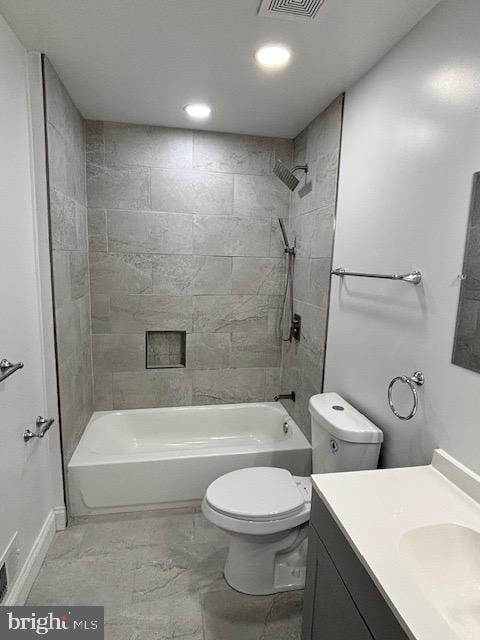 full bathroom featuring tiled shower / bath, vanity, and toilet