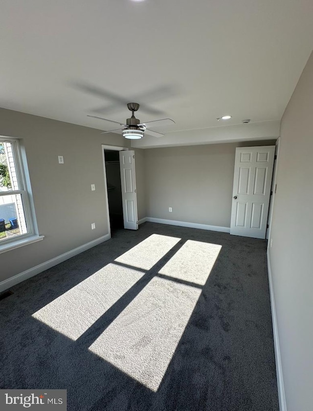 unfurnished bedroom featuring dark colored carpet, ceiling fan, and a closet