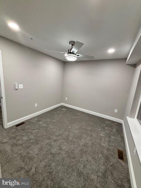 empty room with dark carpet and ceiling fan